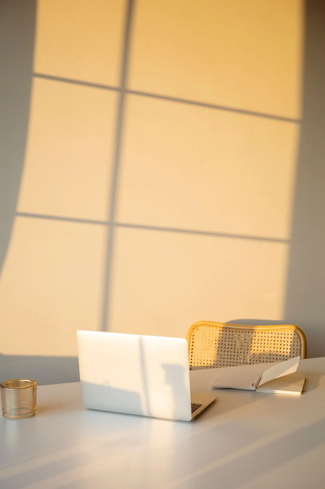 Laptop and woven chair at a desk in warm golden sunlight